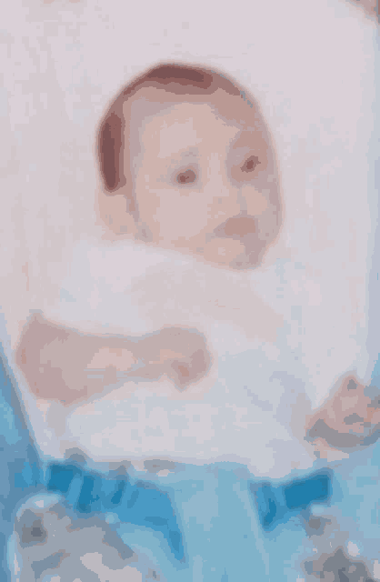 a baby is sitting in a stroller with a blue belt around his waist .