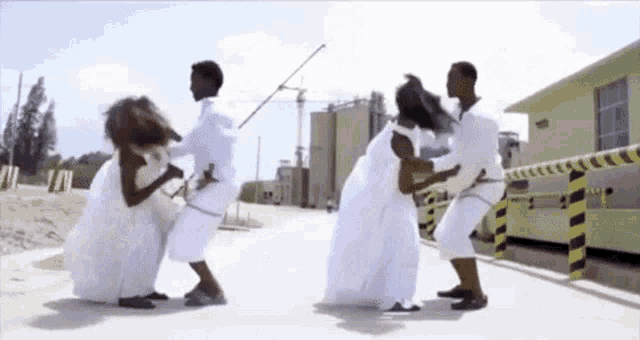 a group of people in white clothes are standing on a sidewalk .
