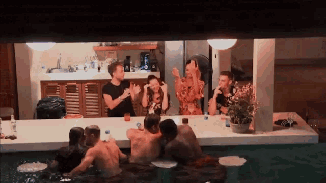 a group of people are gathered in a pool at night