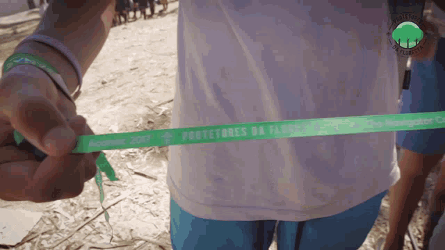 a person holding a green ribbon that says protetores da floresta on it