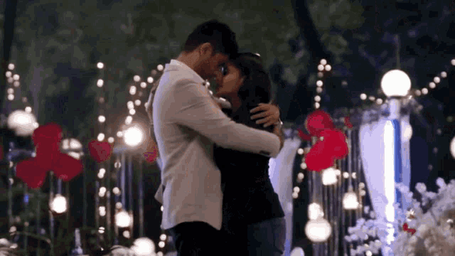 a man and a woman are hugging and kissing in front of lights