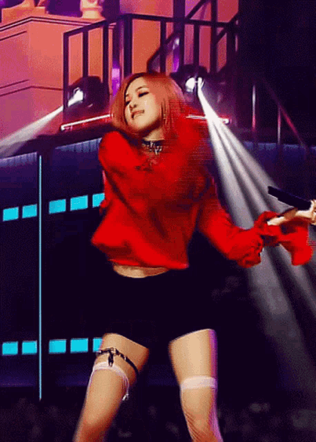 a woman in a red shirt and black shorts is dancing