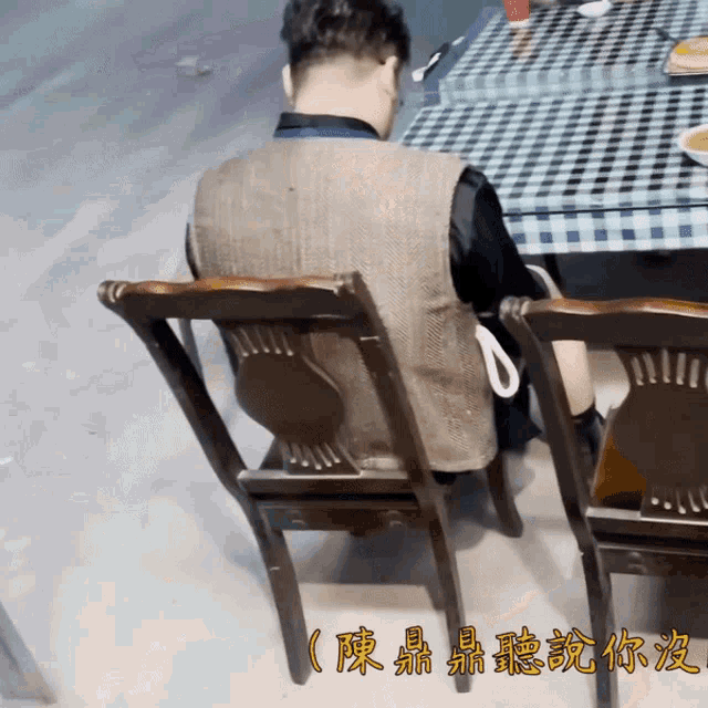 a man sits in a chair in front of a checkered table with chinese writing on it