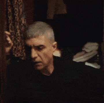 a man in a black shirt holds his hand to his head