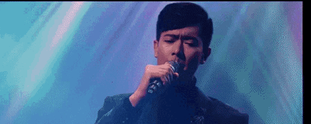 a man is singing into a microphone on stage .
