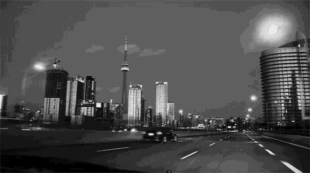 a black and white photo of a city at night with a tower in the background