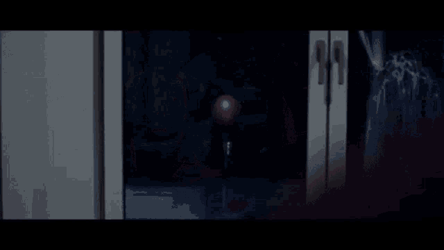 a red balloon is hanging from a string in a dark room .