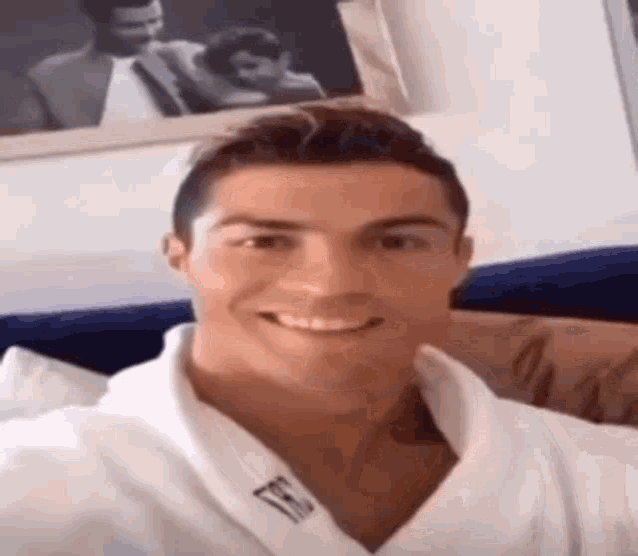 a man in a white robe is smiling for the camera while sitting on a couch .
