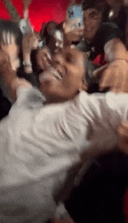 a man in a white shirt is laying on the ground in a crowd of people .