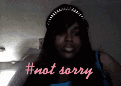 a woman wearing a hat and a blue tank top says #not sorry