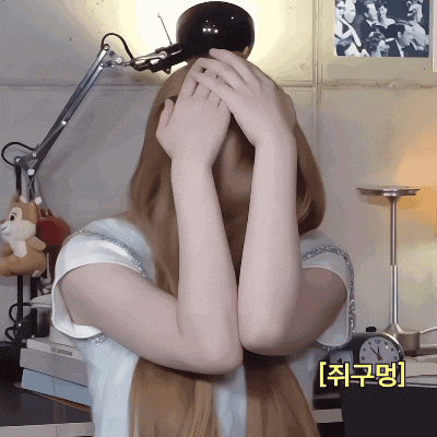 a woman covering her face with her hands in front of a lamp