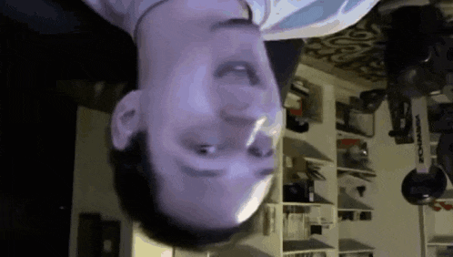 a man 's head is upside down in a room with a sign on the wall that says ' workout '