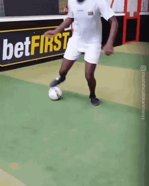 a man kicks a soccer ball in front of a sign that says bet first