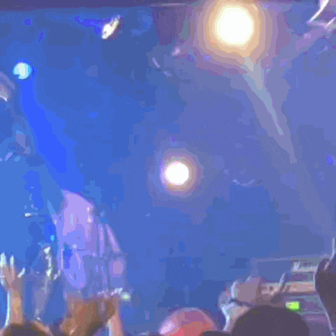 a blurry picture of a crowd at a concert with a few people holding their hands in the air