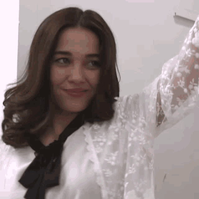 a woman wearing a white lace shirt with a black bow