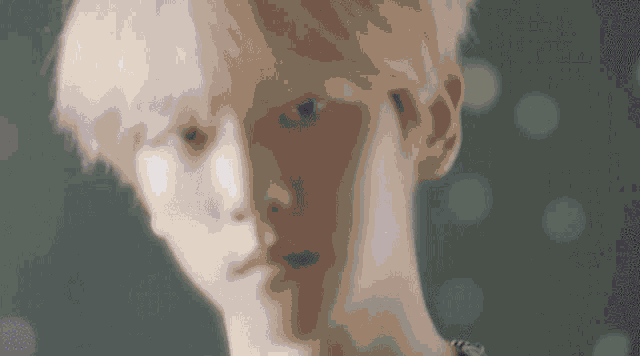 a close up of a young man 's face with pink hair .