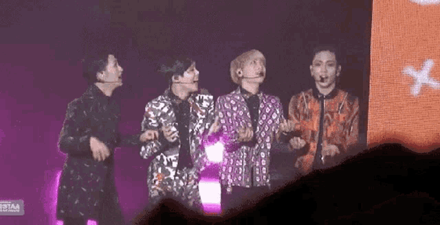 a group of men are standing on a stage holding microphones .