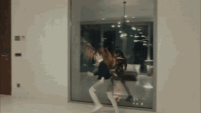 a woman is walking through a room with a large glass wall