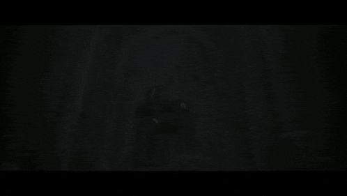 a woman in a black costume is standing in a dark room