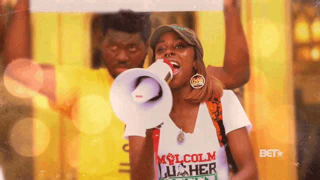 a woman is holding a megaphone and wearing a shirt that says malcolm luther