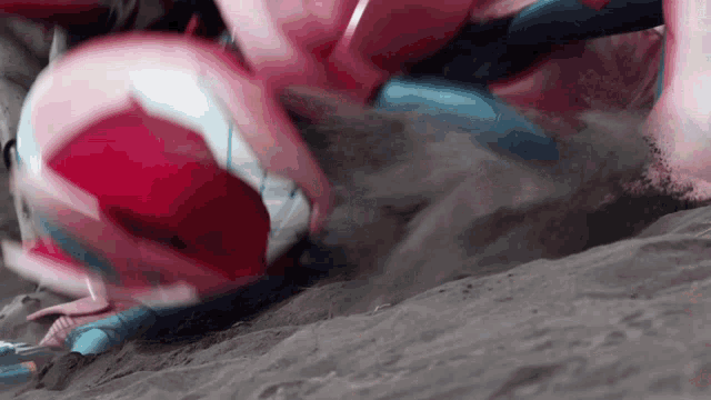 a person in a pink and blue costume is laying on the sand .