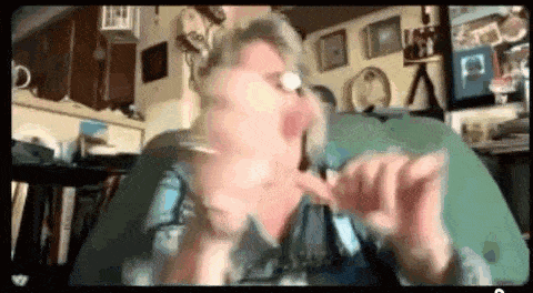an older woman is sitting on a couch in a living room making a funny face .