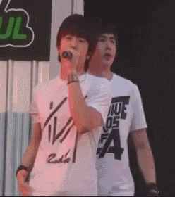 two young men are standing next to each other in front of a microphone .