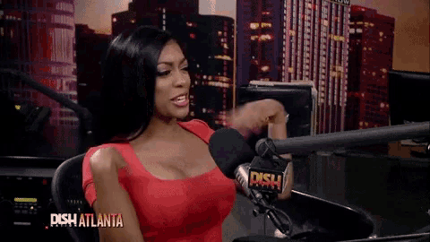 a woman in a red dress is sitting in front of a microphone that says dish on it