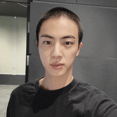 a man with a shaved head is wearing a black t-shirt