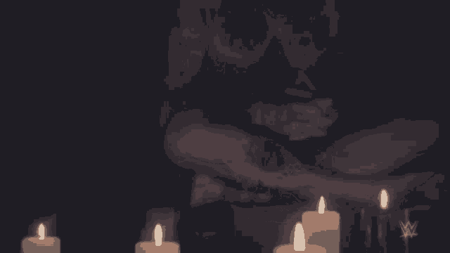 a man sits in a dark room with candles and a w logo