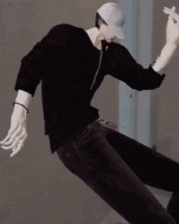 a man wearing a hat and a black shirt is dancing in a room .