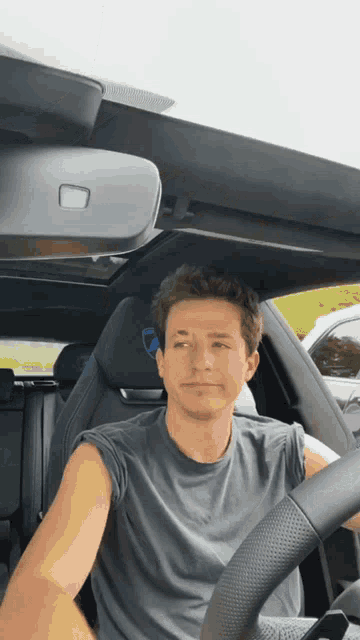 a man in a black shirt is driving a black car