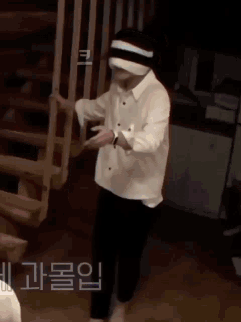 a man in a white shirt and black pants is standing next to a staircase .