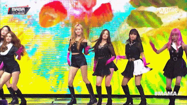 a group of women are dancing on a stage with a colorful background .