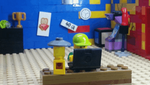 a lego figure sits at a desk with a laptop and a sign that says 404 on it