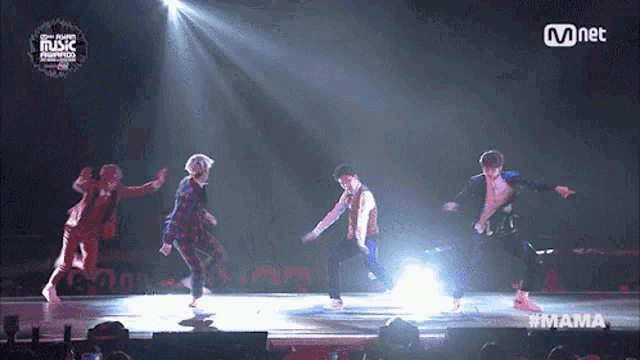 a group of young men are dancing on a stage with mnet written on the bottom
