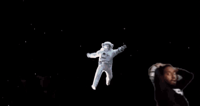 a man with glasses and a black turtleneck is holding his hands up in the air .