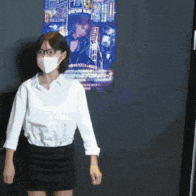 a woman wearing a mask and glasses is standing in front of a poster that says welcome