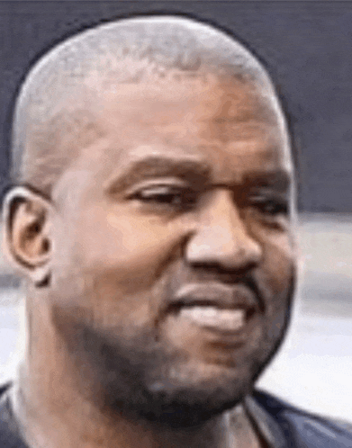 a man with a shaved head and a beard is smiling .