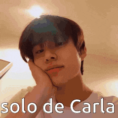 a young man is holding his hand to his face with the words solo de carla written below him .