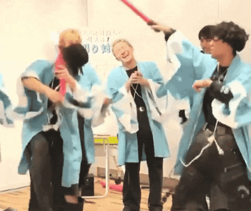a group of people in blue kimonos are dancing in a room
