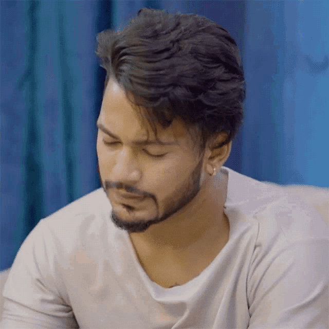 a man with a beard wearing a white shirt looks down