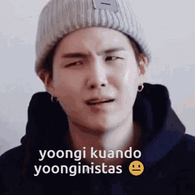 a young man wearing a beanie and a black hoodie with the words yoongi kuando yoonginistas on the bottom