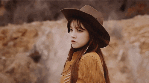 a woman wearing a brown hat and fringed jacket