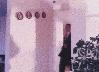 a man in a suit is standing in a hallway with clocks on the wall
