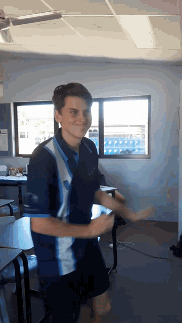 a boy in a blue and white shirt is dancing in a room