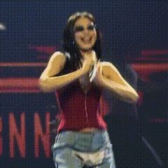 a woman in a red top is dancing in front of a sign that says ' i 'm ' on it