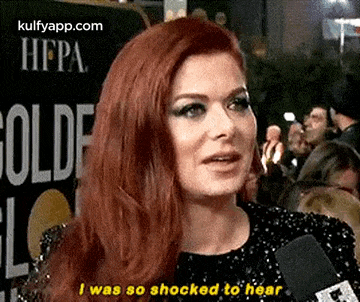 a woman with red hair is talking into a microphone and saying i was so shocked to hear .