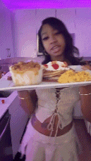 a woman is holding a tray of food in her hands in a kitchen .
