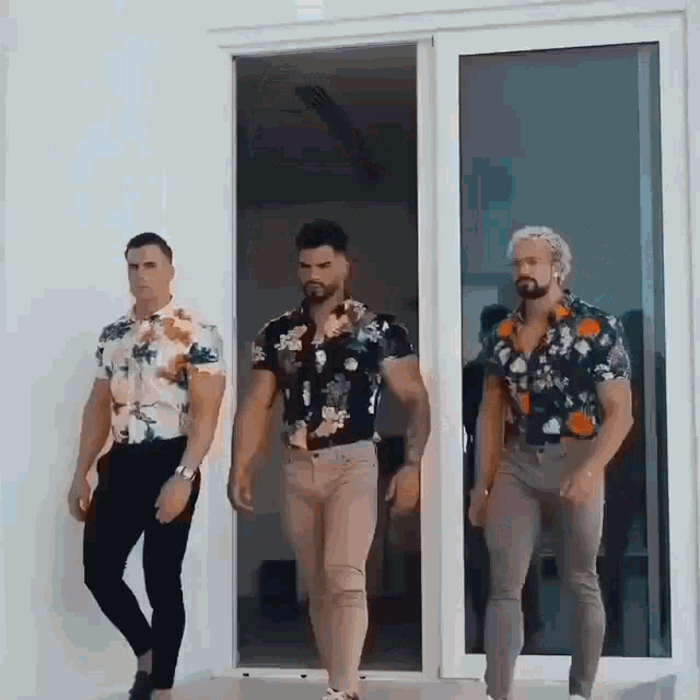 three men are standing in front of a glass door .
